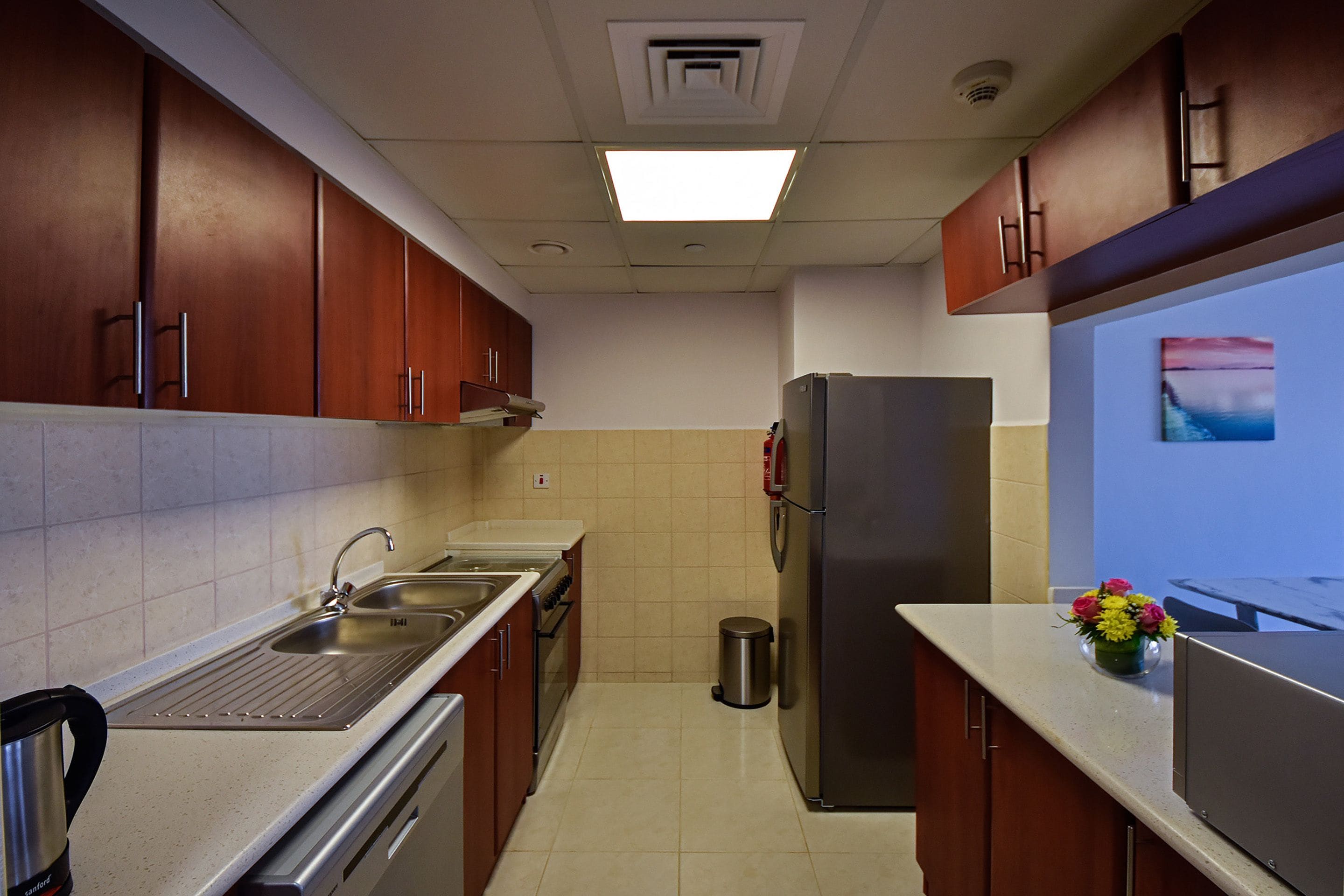 A modern kitchen with stainless steel appliances, a sink, and wooden cabinets.