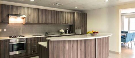 A modern kitchen with wooden cabinets, a built-in gas stove, an oven, a sink, and a breakfast bar.