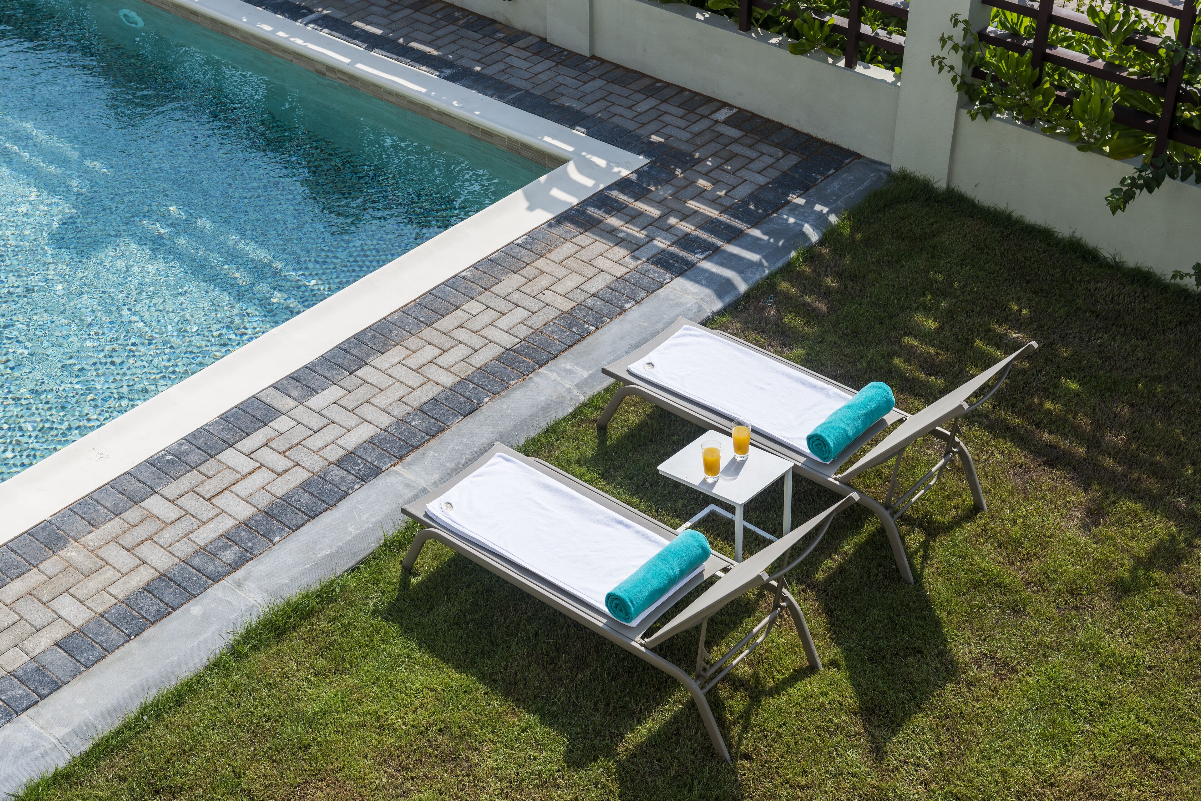 A poolside area with two sun loungers, a small table with a towel, and a glass of orange juice.