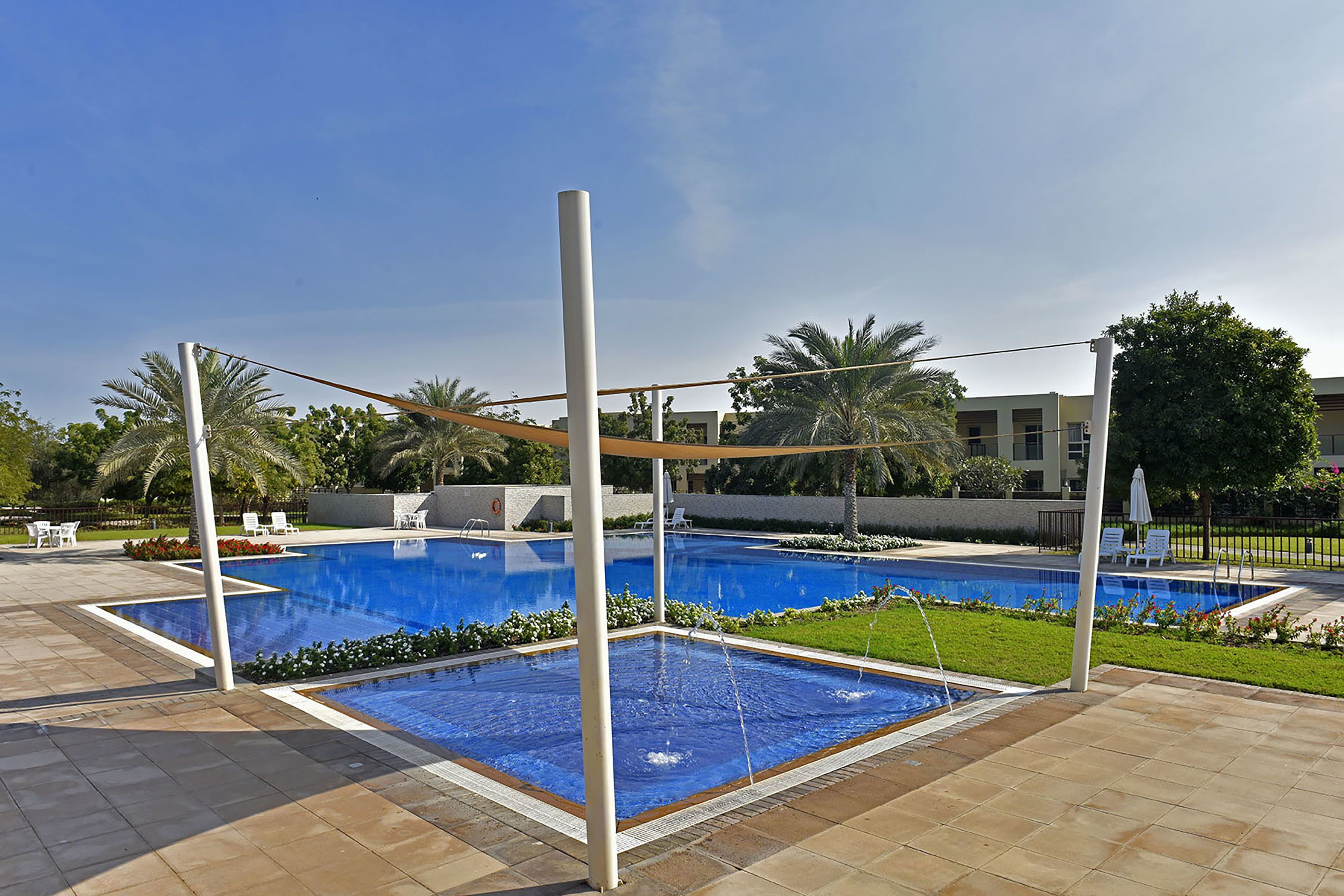 Une piscine à l’eau d’un bleu cristallin, entourée d’une terrasse carrelée et de palmiers.