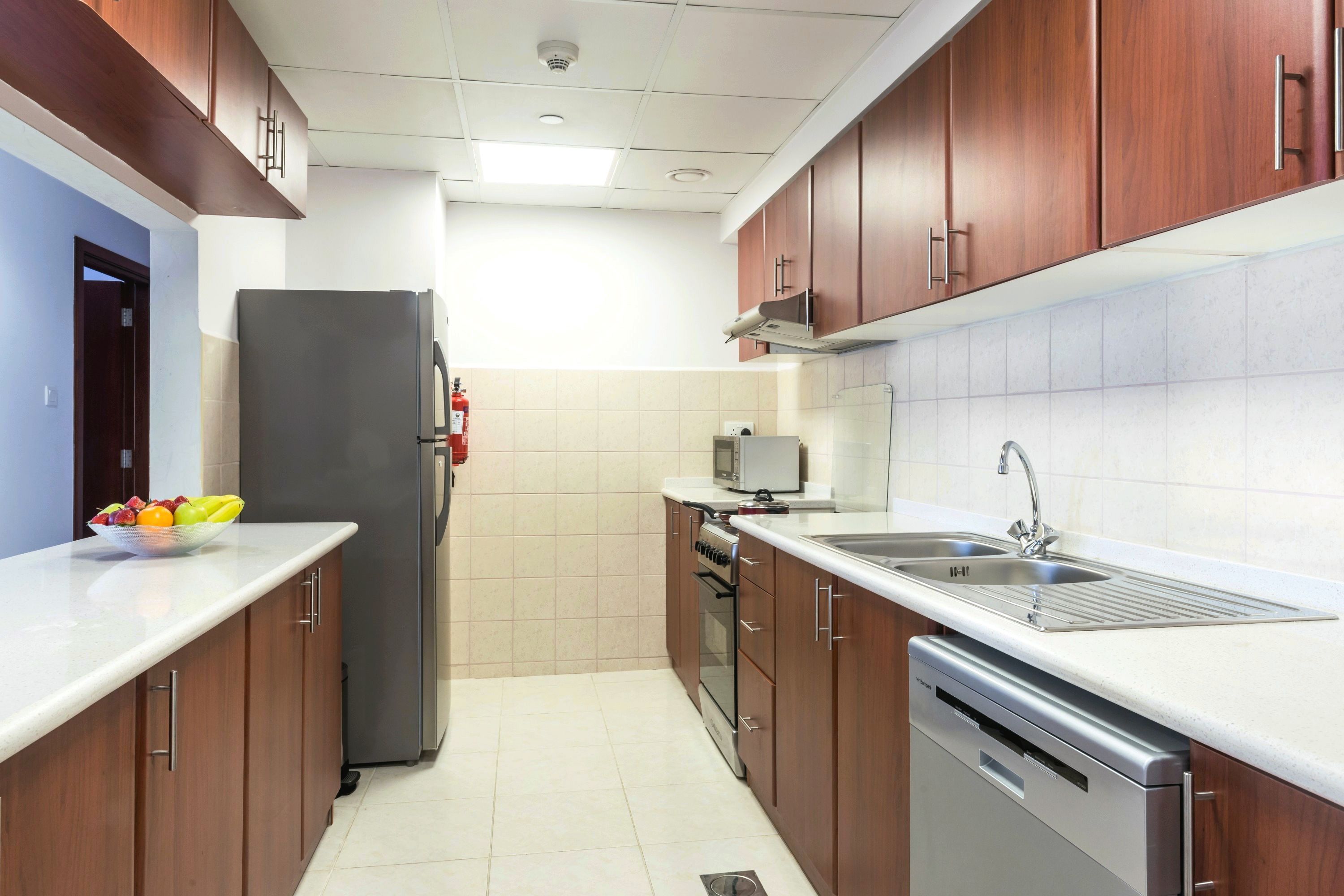 A modern kitchen with wooden cabinets, a stainless steel refrigerator, an oven, a dishwasher, and a sink.