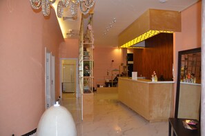 A reception area with a wooden counter, a decorative chandelier, and a reception desk with various items on it. - Jannah Hotel Apartments & Villas (Ras Al Khaimah)