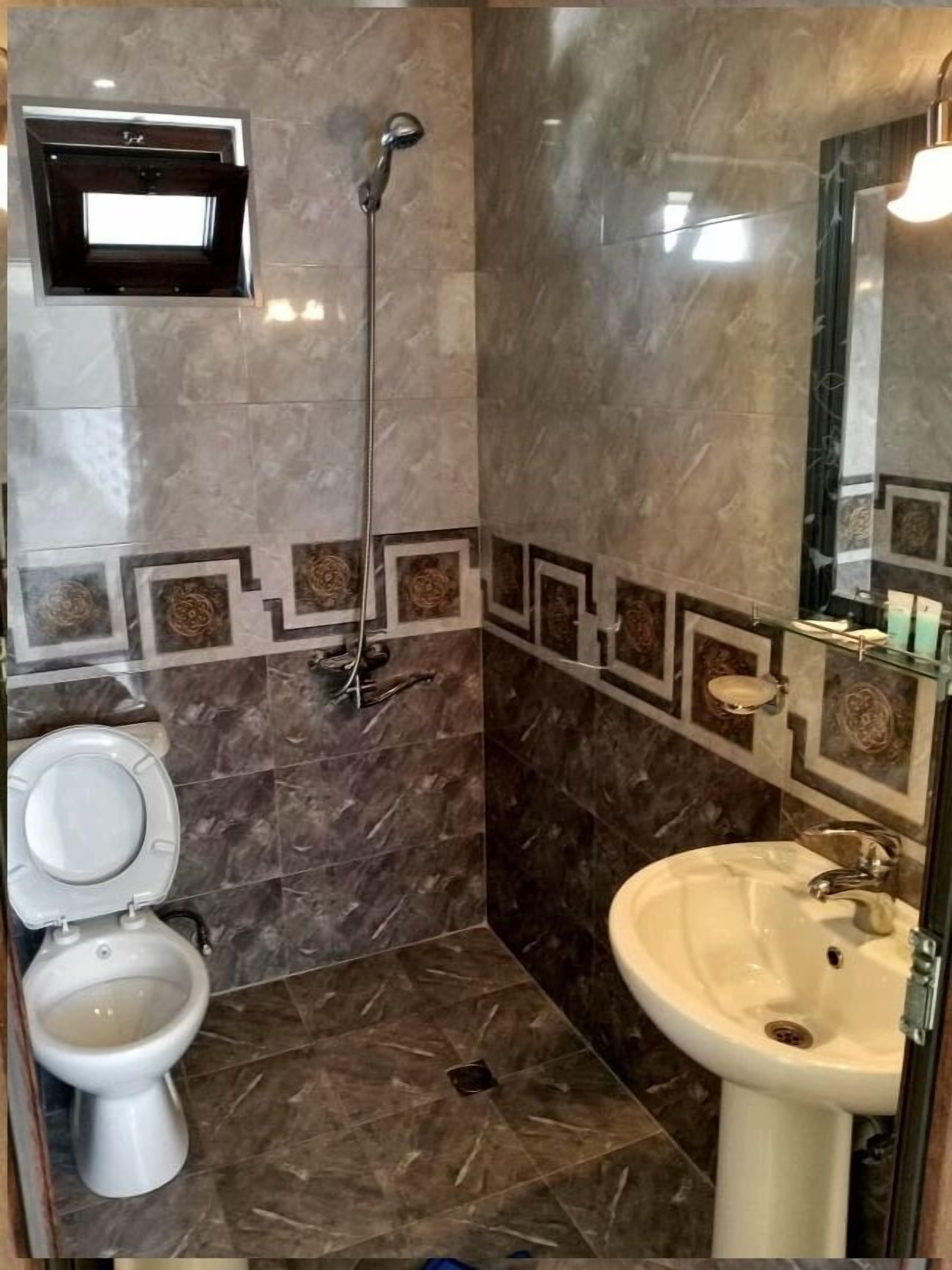 A bathroom with a toilet, sink, and shower.