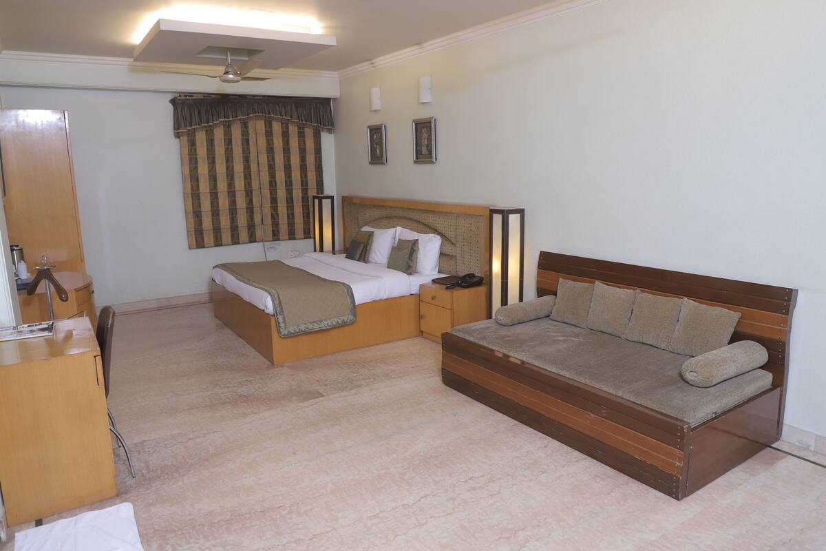 A bedroom with a bed, a sofa, a desk, and a wardrobe.