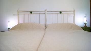 Una cama con cabecera de madera, dos lámparas de noche y un adorno verde en la cabecera.