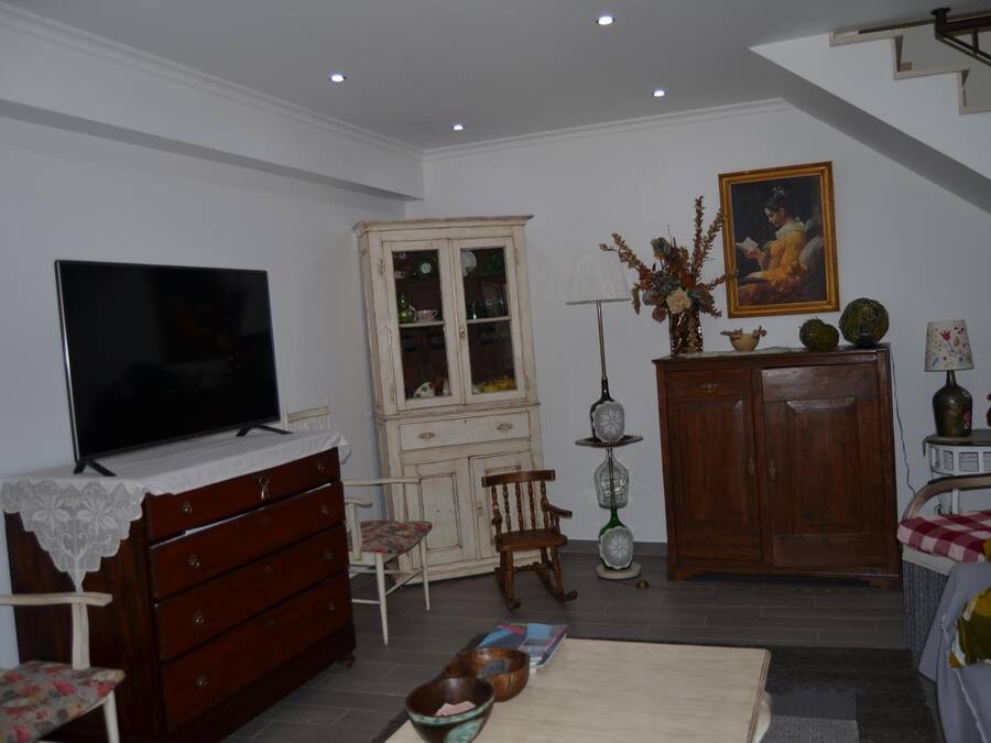Una sala de estar con televisor, muebles de madera, un cuadro y una escalera.