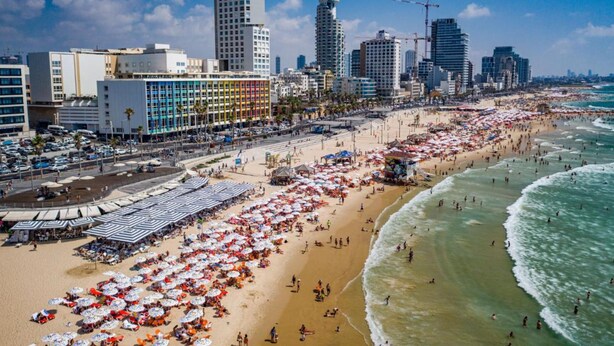 A beachside cityscape with a wide promenade lined with beach umbrellas and sun loungers. - Dream Beach TLV Boutique Hotel (Tel Aviv)