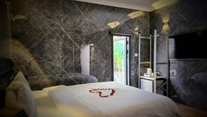 A modern bedroom with a marble wall, a bed with a heart-shaped decoration, a desk, and a TV. - Dream Beach TLV Boutique Hotel (Tel Aviv)