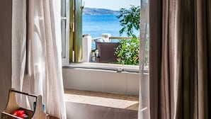 Una habitación con vista al mar, una mesa con un objeto rojo y una ventana con cortinas.