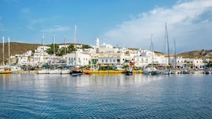 Un pueblo costero con edificios blancos, un puerto deportivo con barcos y un cielo azul despejado.