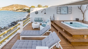 Una terraza con sillones de descanso y un jacuzzi con vista a la playa.