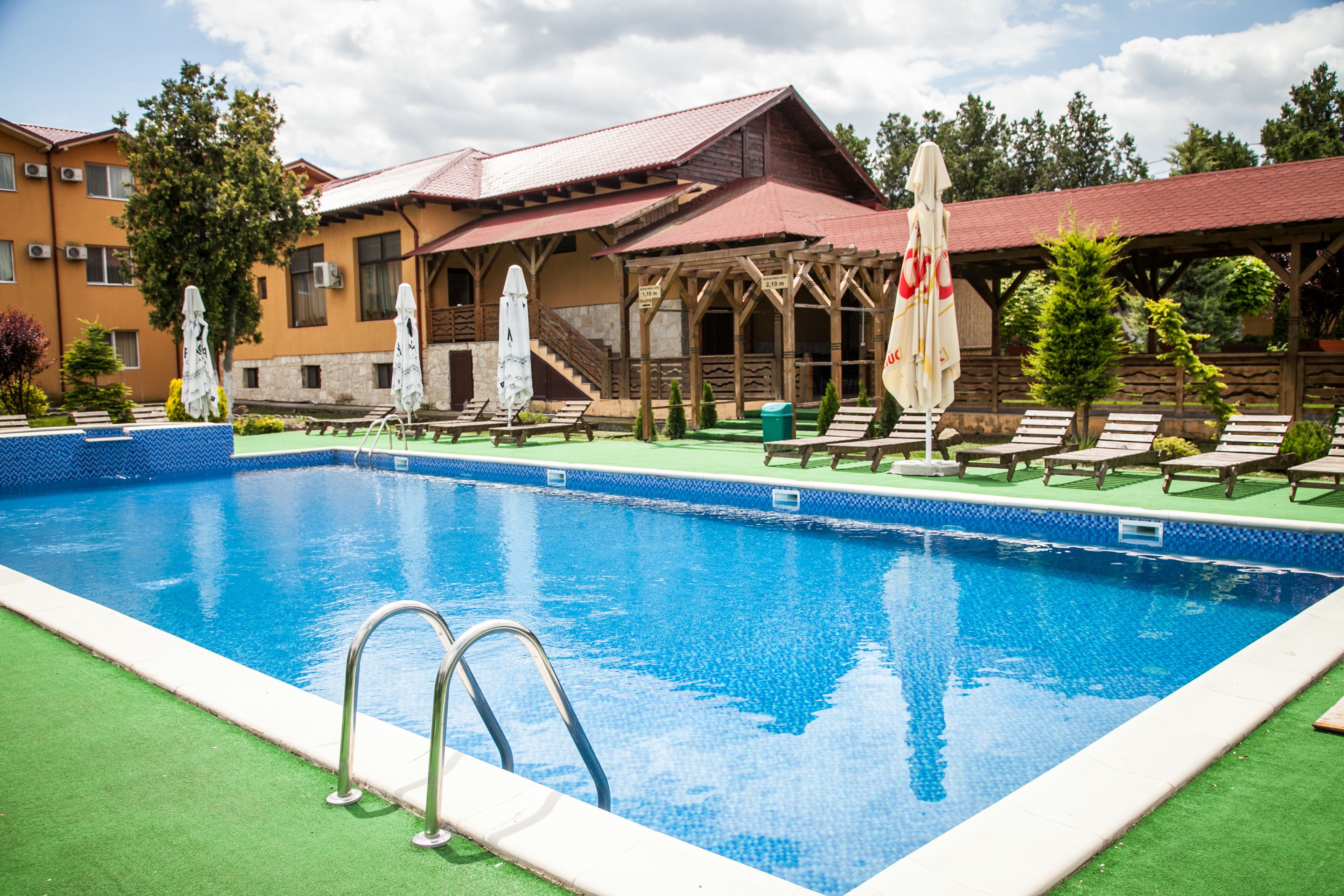 Een buitenzwembad, parasols bij het zwembad en ligstoelen
