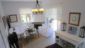 Una sala de estar con sofá, sillón, mesa de centro, chimenea y candelabro.