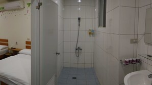 Une petite salle de bain propre, équipée d’une douche, d’un lavabo et d’un miroir.