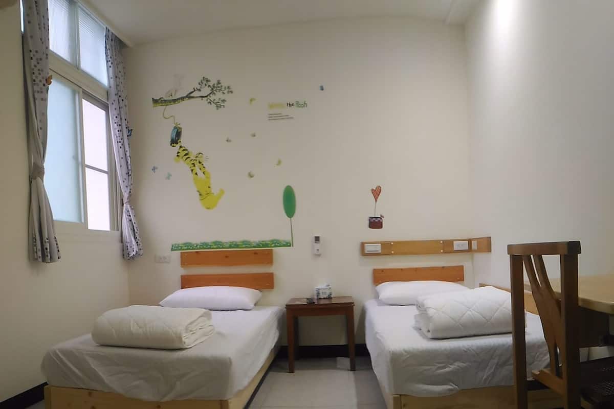 Una habitación con dos camas de madera, una mesita y una silla.
