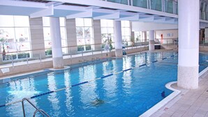 Ein Hallenbad mit deutlichen Fahrbahnen, großen Fenstern und einem gefliesten Boden.