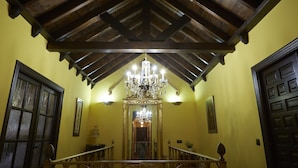 A room with a wooden ceiling, a chandelier, and a door with a decorative panel. - Posada La Casa de Las Manuelas (Horcajo de las Torres)