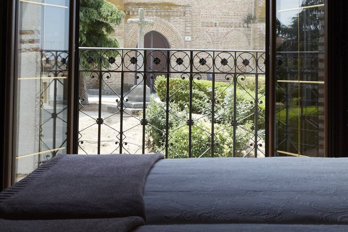 Ein Zimmer mit großem Fenster mit Blick auf ein traditionelles Gebäude mit Ziegeldach und Backsteinwand.