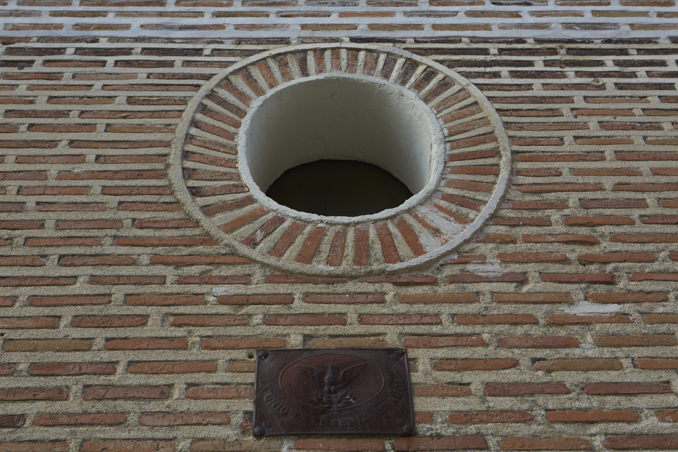 A circular brick structure with a plaque below it.