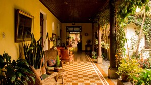 Un pasillo con suelo a cuadros, muebles de mimbre y plantas en macetas.