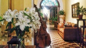 Una habitación con piso estampado, un sofá, una silla, una mesa con un florero de flores blancas y un bolso grande en el suelo.