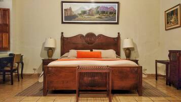Una cama de madera con un cabecero decorativo, dos lámparas de noche y un cuadro de paisaje enmarcado encima.