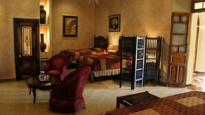 Habitación de hotel con dos camas, un sillón rojo, una mesita pequeña y una escalera de madera.