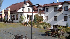 A building with a red-tiled roof, a sign reading "CAFFE RESTAURANT," and outdoor seating with umbrellas. - Pension Všeruby (Vseruby)