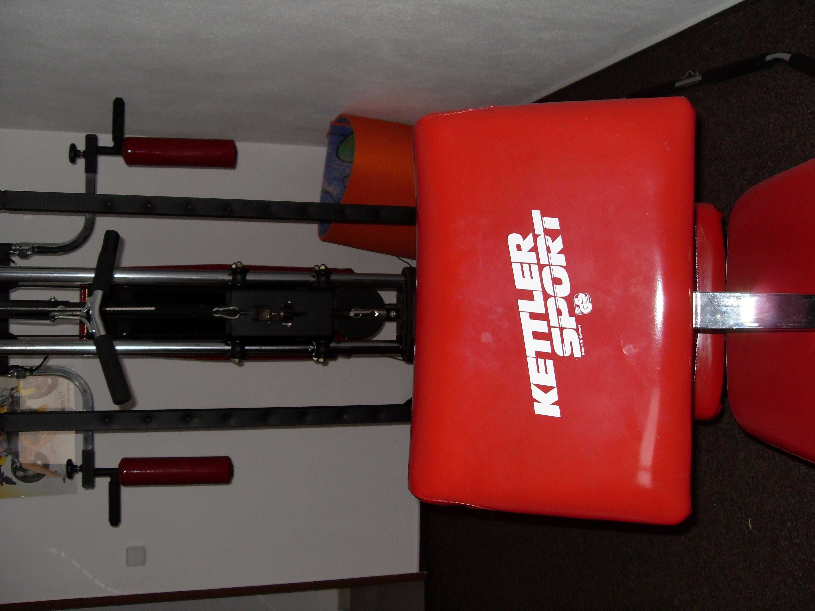 Een rode kettlebell met de tekst 'Kettlebell Sport' erop, bevestigd aan een muur.