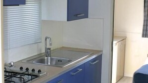 A compact kitchenette with blue cabinets, a stainless steel sink, and a gas stove. - Pension Všeruby (Vseruby)