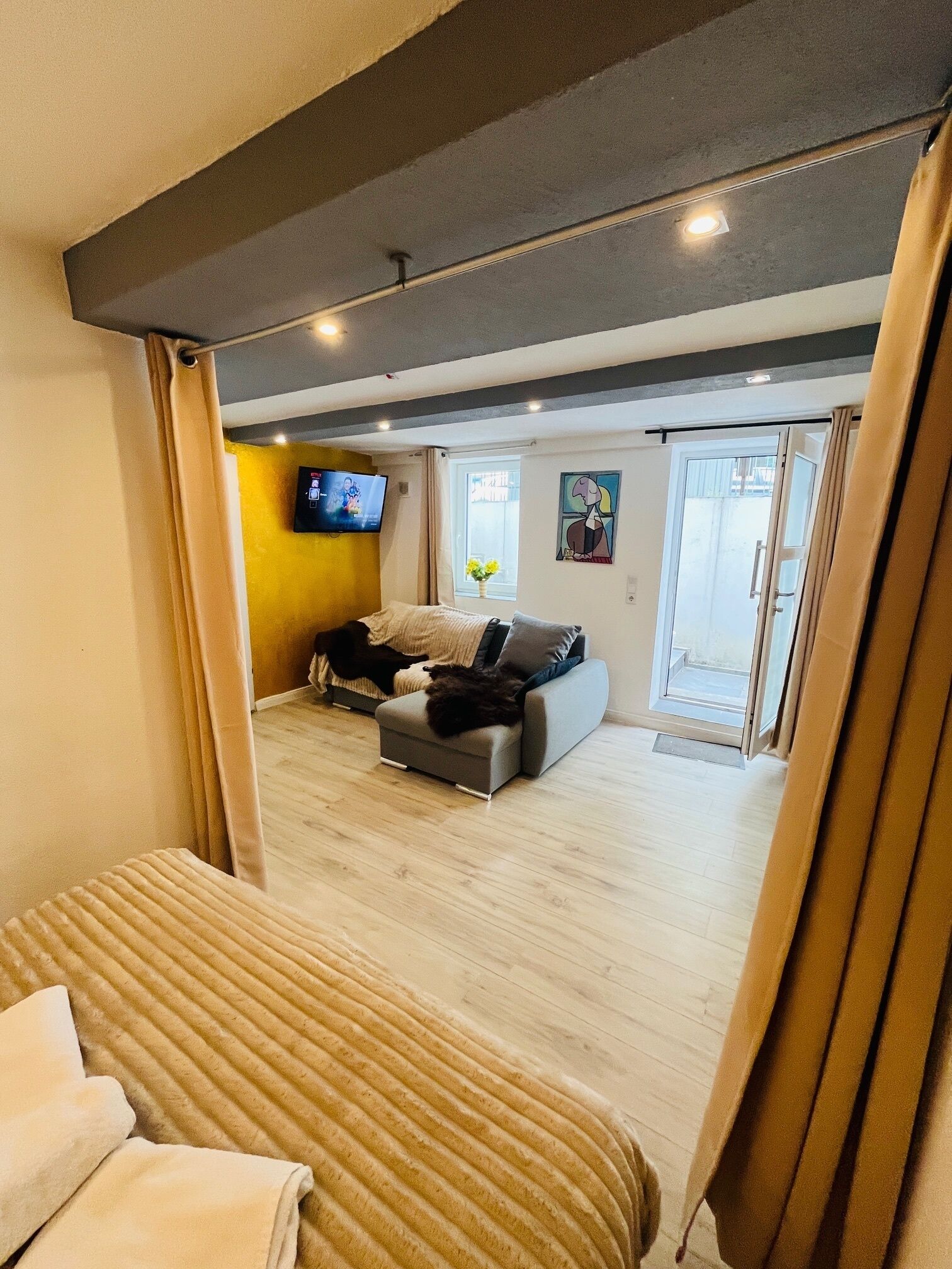 Een moderne woonkamer met een bank, een televisie en een groot raam.