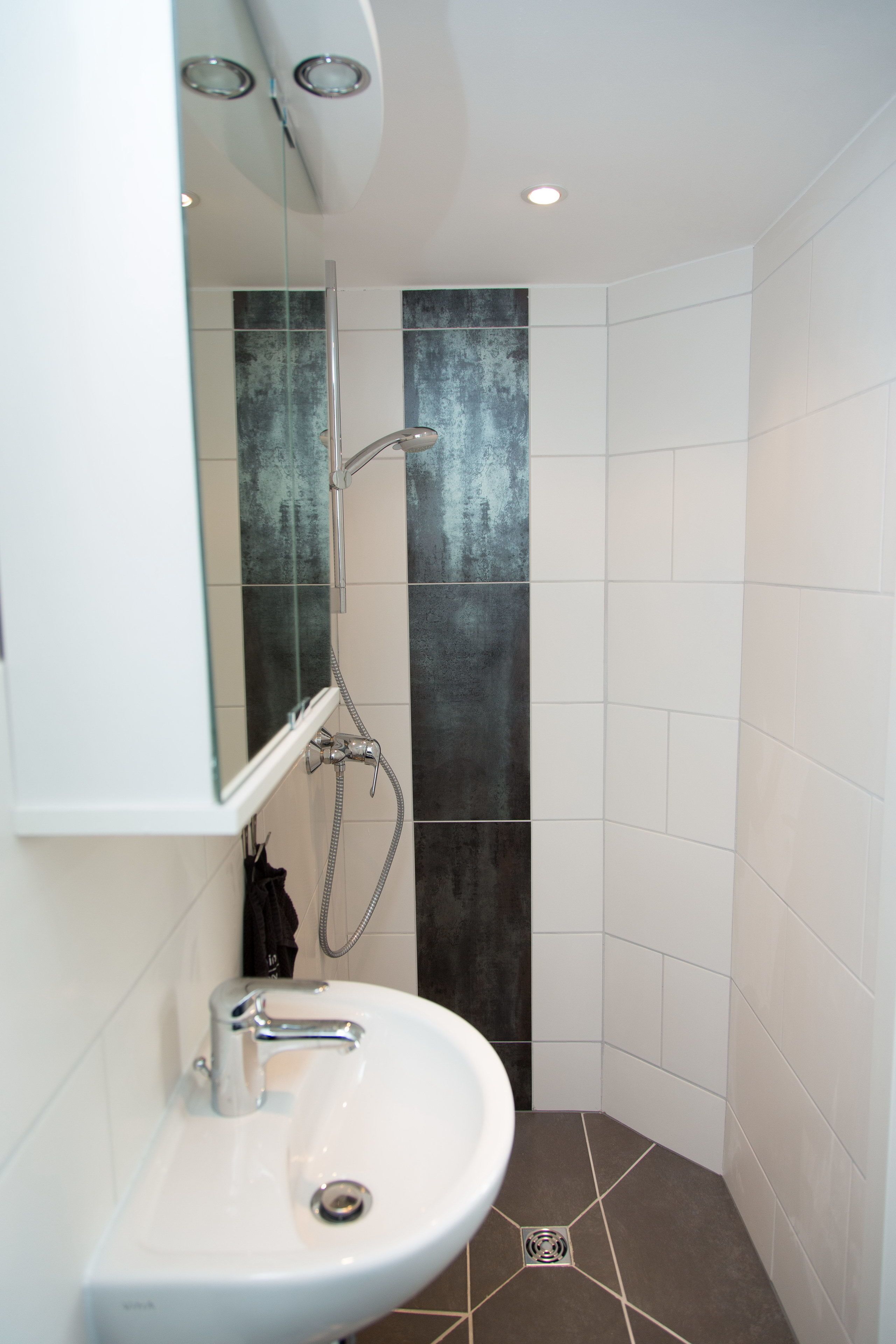 A modern bathroom with a white sink, a mirror, and a shower with a glass door.