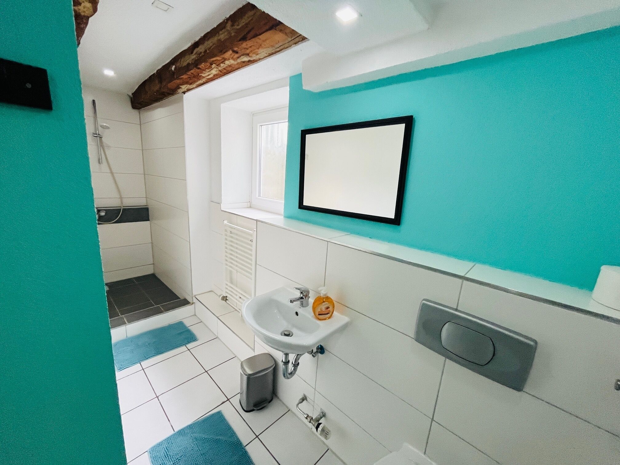 A bathroom with a white sink, a mirror, and a shower.