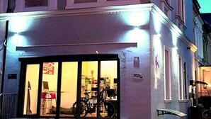 A building with a large glass storefront, a visible Coca-Cola sign, and a bicycle parked outside. - Feldhouse (Bremen)