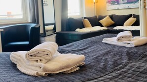 A hotel room with a bed, a chair, a sofa, a large mirror, and a painting on the wall. - Feldhouse (Bremen)