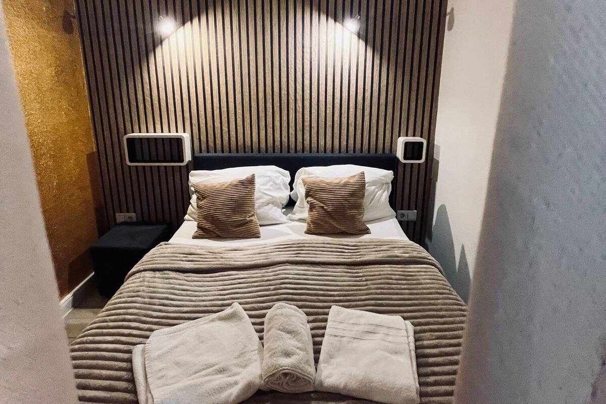 A neatly made bed with striped bedding, two pillows, and a folded towel on the bed.