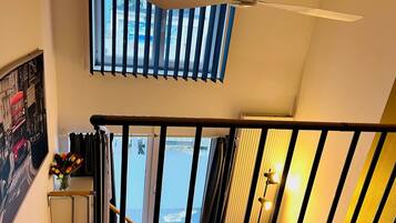 A staircase with a black railing, a ceiling fan, and a window with blinds.