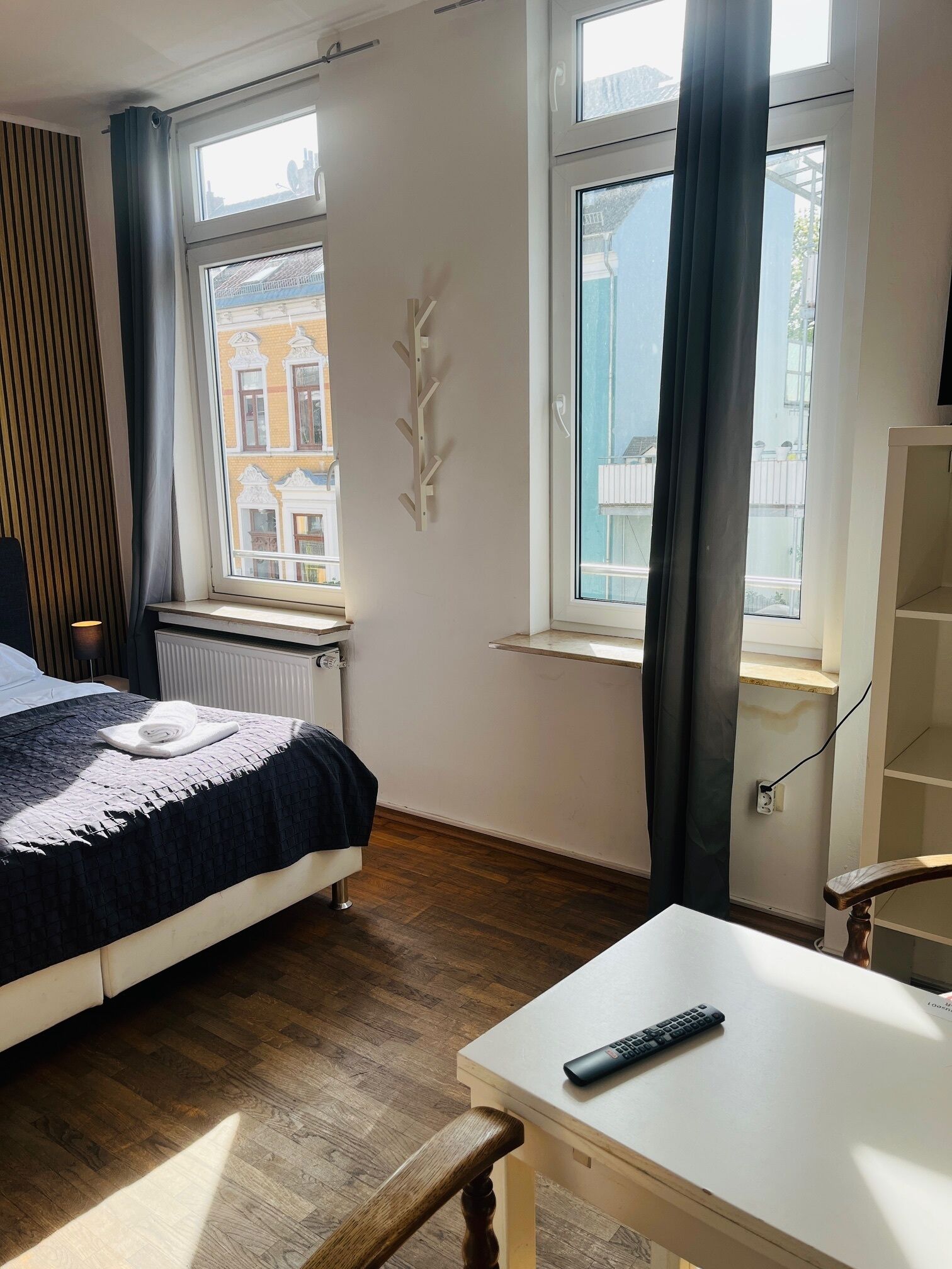Un dormitorio con cama, escritorio y ventana con cortinas.