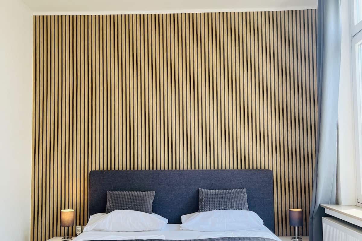 A hotel room with a bed, a ceiling fan, and a window with curtains.