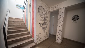 A staircase with a hand-painted design on the wall, a target on the wall, and a door at the end. - Hostel do Bosque (Rio de Janeiro)