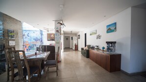 A spacious living area with a dining table, chairs, a sofa, and a wooden cabinet. - Hostel do Bosque (Rio de Janeiro)