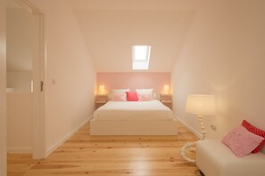 A bedroom with a bed, bedside lamps, a window, and a door. - Casasupertubos (Peniche)
