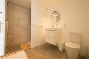 A bathroom with a shower, toilet, sink, and a mirror. - Casasupertubos (Peniche)