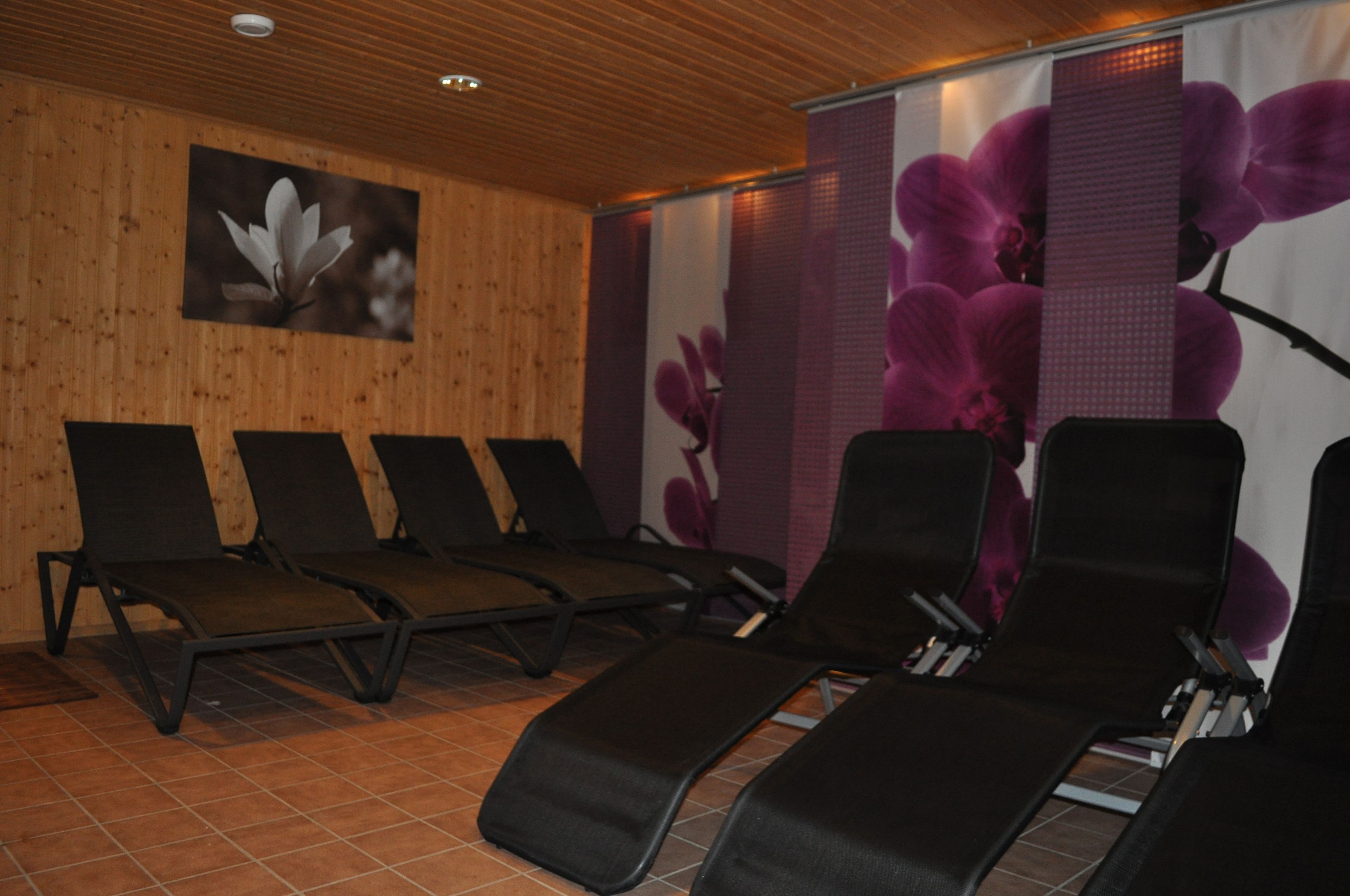 A room with wooden panel walls, a tiled floor, and four reclining chairs.