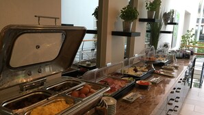 Un bufé con diversas opciones de comida, incluyendo carnes, quesos y frutas.