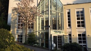Un hotel con entrada de vidrio moderna, fachada tradicional y un letrero que indica que se encuentra en Friedrichstrasse.