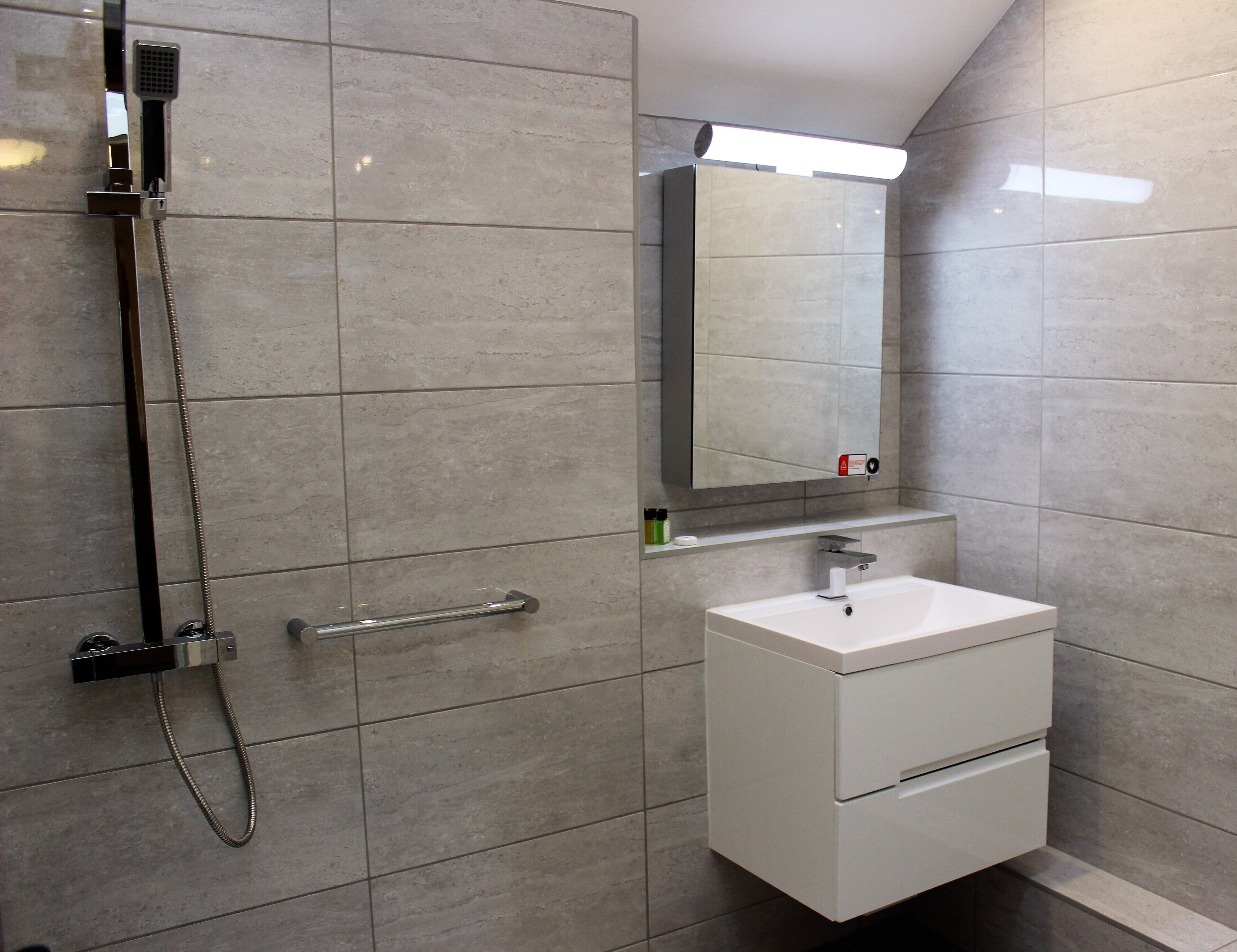 Un bany modern amb dutxa, un lavabo i un mirall.