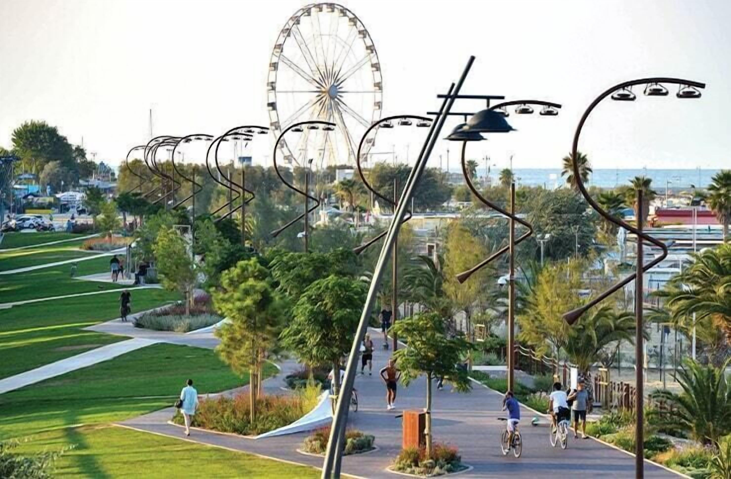 A park with a Ferris wheel, pathways, and street lamps.