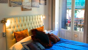 Ein Schlafzimmer mit einem großen Bett, einem Nachttisch und einem Fenster mit Blick auf einen Balkon.
