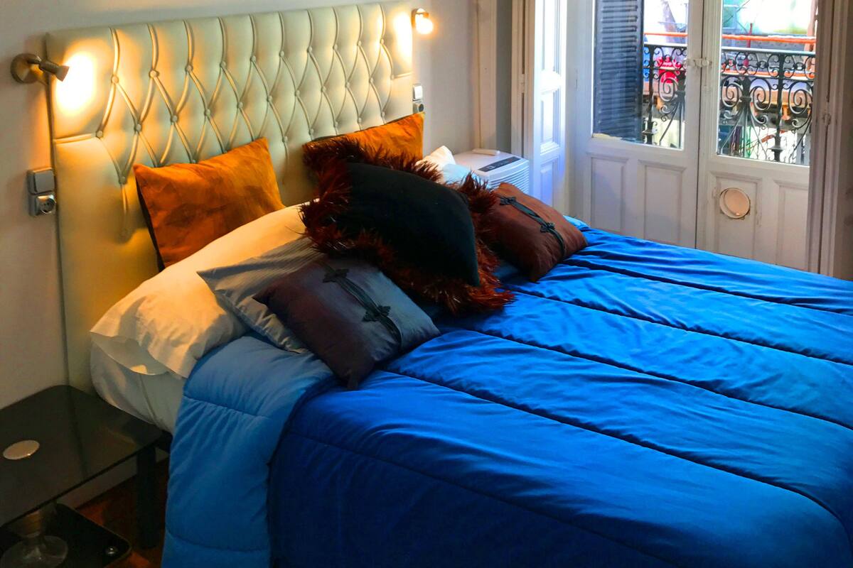 Une chambre à coucher avec un grand lit, une table de chevet et une fenêtre donnant sur un balcon.